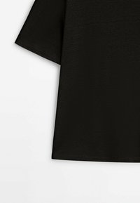 T-shirt noir à manches courtes avec un design simple et uni, présenté sur un fond blanc.