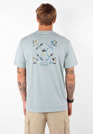 T-shirt en coton bleu clair avec un graphique coloré de papillon au dos, à manches courtes et au col rond.