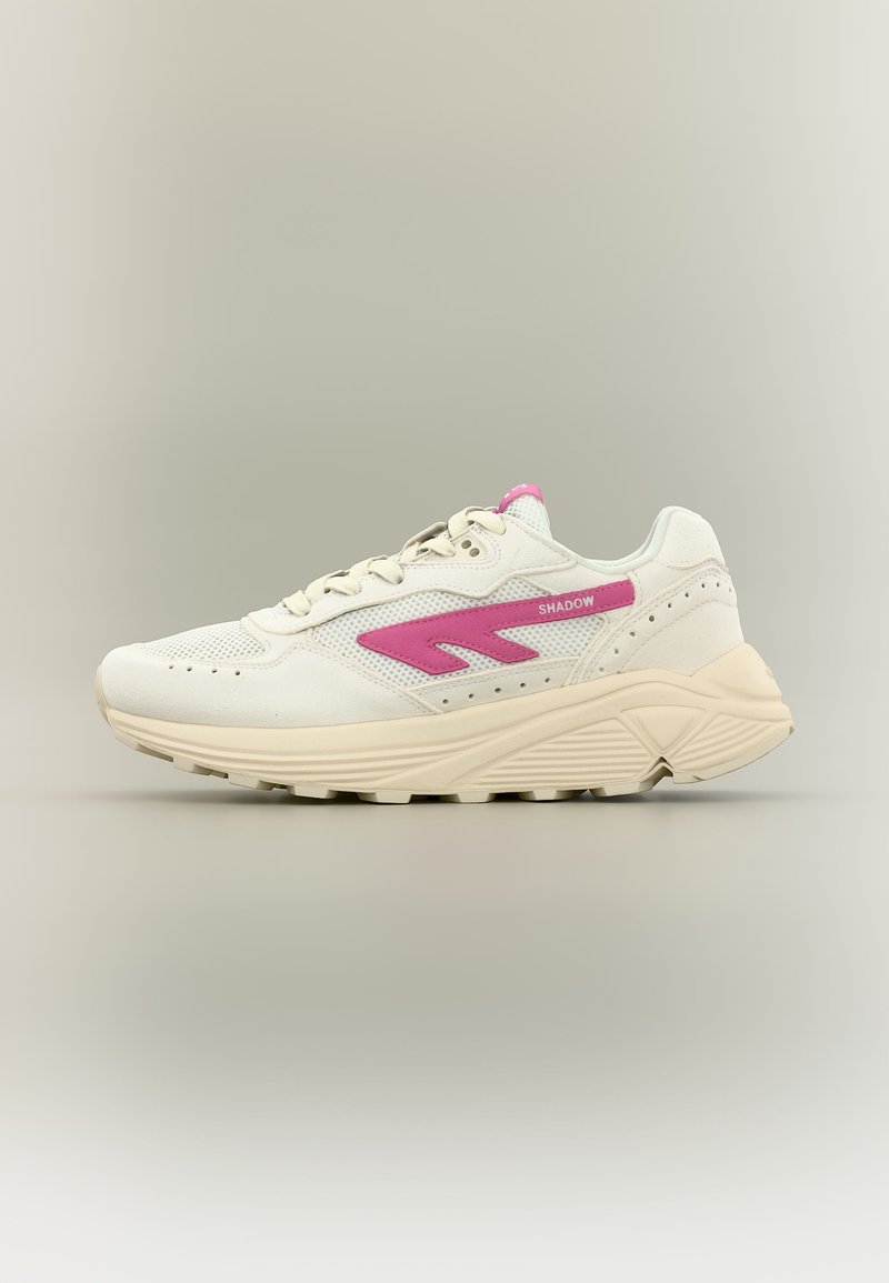 Baskets blanches et beiges avec une semelle épaisse, dessus en mesh et cuir, accent rose en forme d'éclair, et texte "SHADOW" sur le côté.