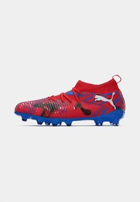 Crampone de football rouge et bleu avec une tige texturée, un ajustement confortable, des motifs géométriques distinctifs et des accents noirs ; il dispose de crampons moulés.