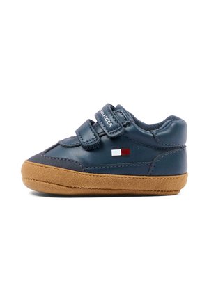 Donkerblauwe peutersneaker met bruine zool, twee klittenbandsluitingen en een klein rood, wit en blauw logo aan de zijkant.