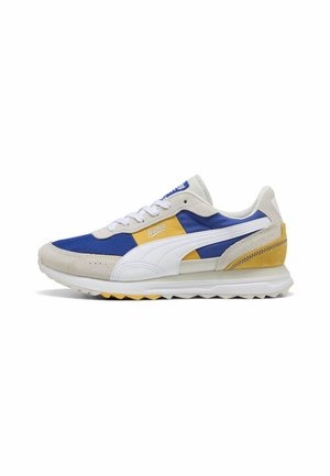 Puma sneakers feature a blue mesh upper, beige suede accents, yellow heel, white stripe, and textured sole with yellow highlights.
