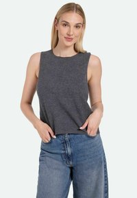 Gray sleeveless top with a crew neck, soft texture, loose fit; worn with high-waisted blue denim jeans. No visible patterns or accents.