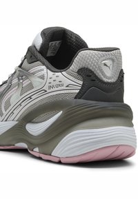 Scarpa atletica grigia e nera con tomaia in rete, dettagli texture e una suola spessa e stratificata con accenti bianchi e rosa.