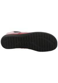 Chaussure en cuir rouge avec un dessus lisse et une semelle noire rembourrée présentant des motifs de profondeur pour l'adhérence. Accents minimaux sur les côtés.