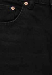 Gros plan sur un tissu denim noir montrant une poche avant avec des rivets en cuivre et des détails de couture.