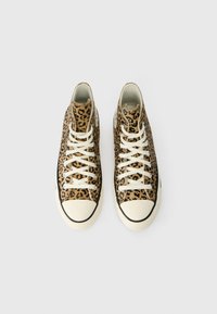 Υψηλές αθλητικές με leopard print ύφασμα και λευκές κορδόνες, στρογγυλή μπεζ καπάκι από καουτσούκ και μαύρη επένδυση κατά μήκος της σόλας.