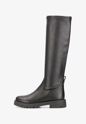 Bottes noires montantes en cuir lisse et texturé, avec une semelle en caoutchouc épaisse et une languette à l'arrière ornée d'un petit accent.