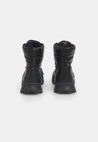 Cizme impermeabile negre cu un design căptușit, talpă din cauciuc texturat și bucle pentru o utilizare mai ușoară. Vedere din spate care evidențiază detaliile cusăturii.
