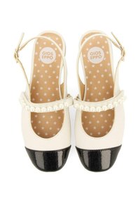 Zapatos slingback blancos con puntera negra brillosa, tira de acento de perlas y plantilla con patrón de estrellas. Material suave similar al cuero.