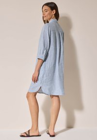 Abito camicia a righe azzurro chiaro con colletto, maniche a tre quarti e spacco laterale. Realizzato in un tessuto morbido e testurizzato.
