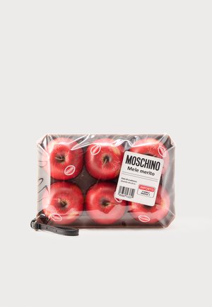 Șase mere roșii cu autocolante Moschino ambalate în folie de plastic transparentă cu o etichetă Moschino și o curea neagră pentru încheietură atașată.