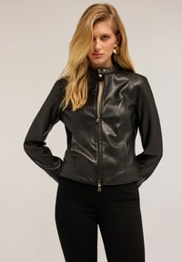 Black leather jacket with a high collar, zip closure, and smooth texture. Features tailored fit and subtle stitching details.