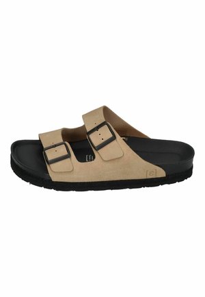 Beige suede slide sandal with two adjustable black buckles, black textured outsole, and smooth black interior lining.