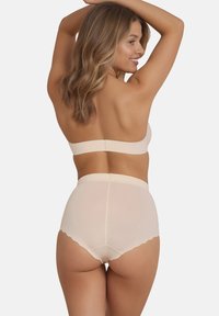 Set de braletă fără cusături bej și chiloți cu talie înaltă. Textură netedă cu margini ondulate, oferind un design minimalist.