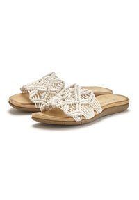 Sandali aperti con una parte superiore intrecciata in stile macramé color crema, posati su una soletta beige e una suola flessibile marrone.