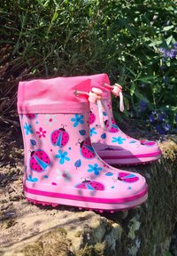 Roze rubberen regenlaarzen met een bloemen- en lieveheersbeestjespatroon, voorzien van een trekkoord aan de bovenkant en een geprofileerde zool voor grip.
