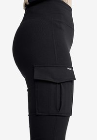 Svarta cargoleggings med sidoficka, elastiskt material och en figurnära design. Slät yta med synliga sömdetaljer.