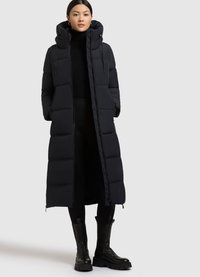 Abrigo acolchado negro largo con capucha, que presenta un diseño acolchado y un cierre frontal. Combina con botas negras hasta el tobillo y leggings.