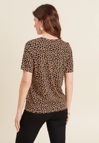 Korte mouwen top in zwart met een bruine giraffeprint. Heeft een ronde halslijn en een fitted snit, gemaakt van zachte, rekbare stof.