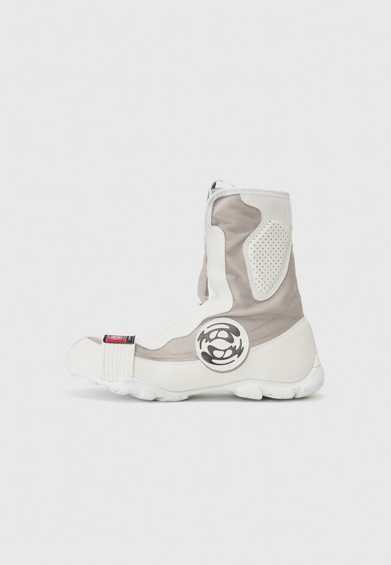 Bottes montantes en maille blanche et gris clair, fabriquées en matériaux synthétiques, dotées d'un logo circulaire, de panneaux texturés et d'une semelle en caoutchouc.