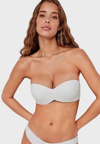 White bandeau bikini top with textured zigzag pattern and no straps, paired with matching bottoms. Soft, lightweight fabric.