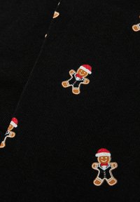 Sort stof med små peberkagemænd iført røde nissehuer og sorte veste, spredt i et gentaget mønster.