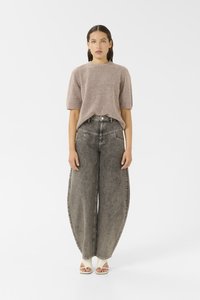 Lyserosa, kortermet genser kombinert med oversized, falmede grå denimjeans. Har vide ben og høy midje, komplementert med beige hæler.