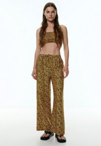 Twee-delig set met een cropped top en brede broek in een gele en zwarte luipaardprint. Gemaakt van lichte, gemêleerde stof.