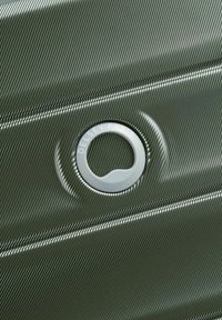 Valigia rigida verde oliva con superficie testurizzata, dotata di una maniglia circolare in metallo argentato con incisione "Delsey Paris".