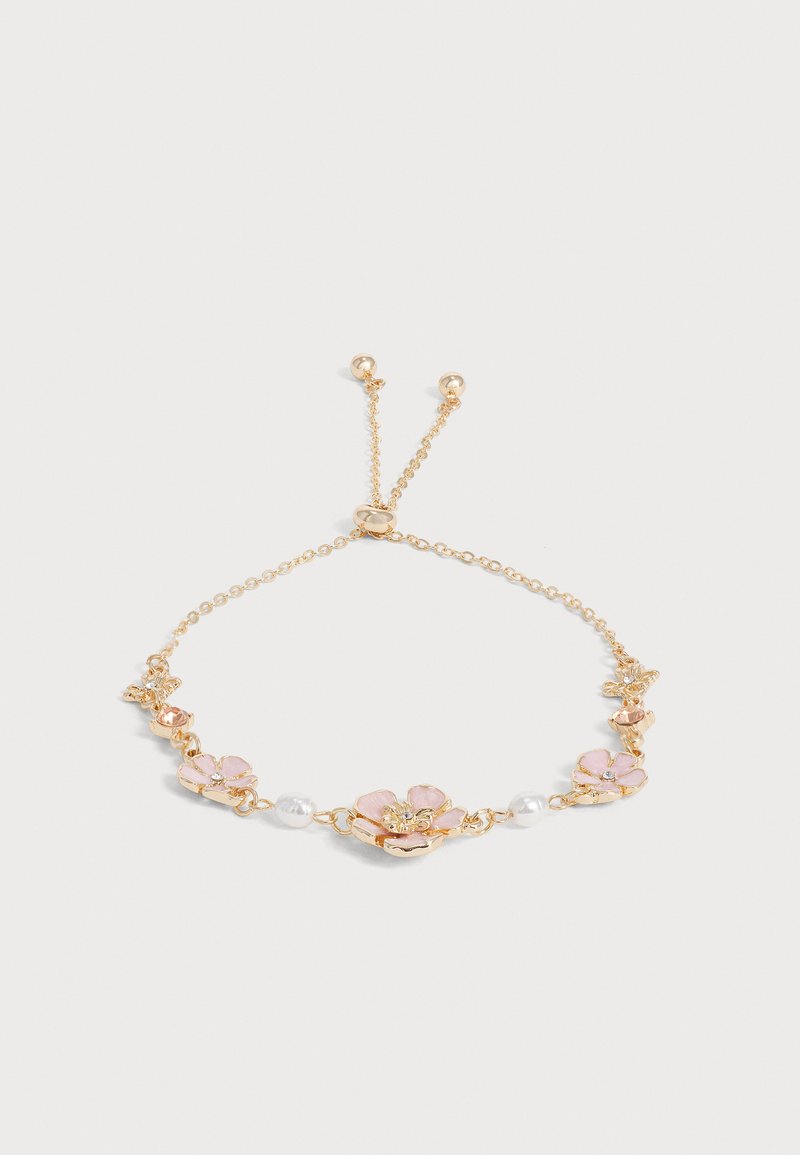 Bracelet délicat en chaîne d'or avec fermoir réglable, orné de petites breloques en forme de fleurs roses et de perles blanches espacées le long de la chaîne.