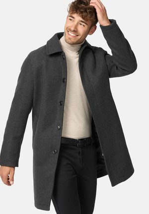 Gray wool coat with a collared neck, five black buttons, and straight-cut design, worn over a light beige turtleneck and black pants.