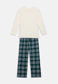 Hosszú ujjú krémszínű felső kerek nyakkal, zöld kockás pizsamanadrággal párosítva, melyen kék és fehér vonalak találhatók, valamint gumis derékpánt.