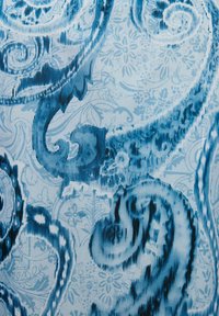 Tessuto blu con un motivo caratterizzato da intricati disegni paisley e floreali su uno sfondo azzurro; texture liscia con tonalità di blu variabili.