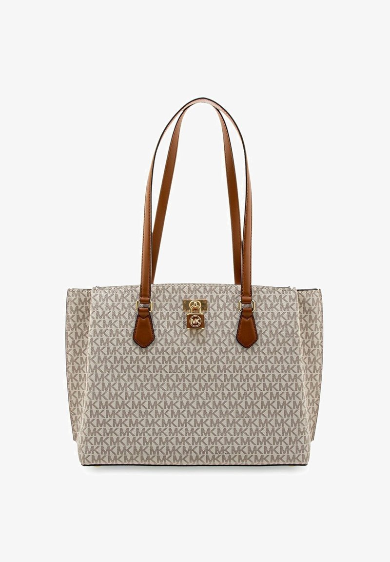 Sac fourre-tout beige avec un logo MK à motifs, des anses en cuir brun, des détails en doré, et un verrou à l'avant. Forme rectangulaire robuste.