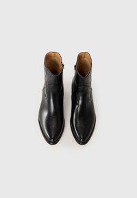 Botas de tobillo negras con un acabado de cuero suave, punteras afiladas y costuras decorativas. Cierre con cremallera lateral y un diseño minimalista.