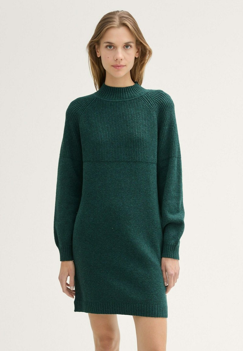 Abito a maglia di colore verde scuro con texture a coste, colletto alto e maniche lunghe. Presenta un design color-block.