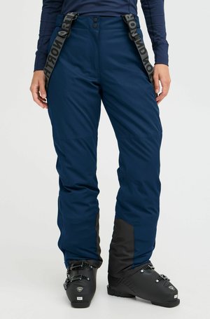 Les pantalons de ski navy sont dotés de bretelles réglables, d'une texture lisse, d'accents renforcés noirs sur le bas des jambes et de fermetures à bouton à l'avant.