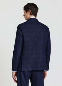 Giacca da completo blu navy con texture, caratterizzata da uno spacco singolo, taglio sartoriale e polsini con bottoni. La vista posteriore mette in risalto un delicato motivo a quadri e il design della rever.
