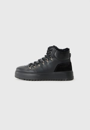 Bottines de randonnée hautes noires avec lacets, dot�ées d'une tige en cuir texturé, d'un col en fourrure et d'une semelle en caoutchouc robuste.