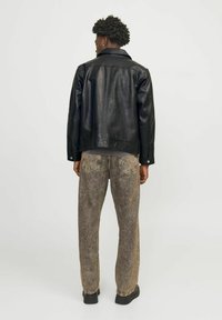 Black leather jacket with a collar, visible stitching, paired with grayish-brown textured jeans and black shoes, viewed from the back.