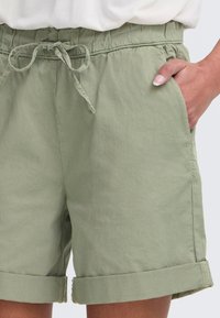 Grønne bomullsshorts med elastisk midje og snor, med sidelommer og oppbrettede mansjetter for et avslappet design.