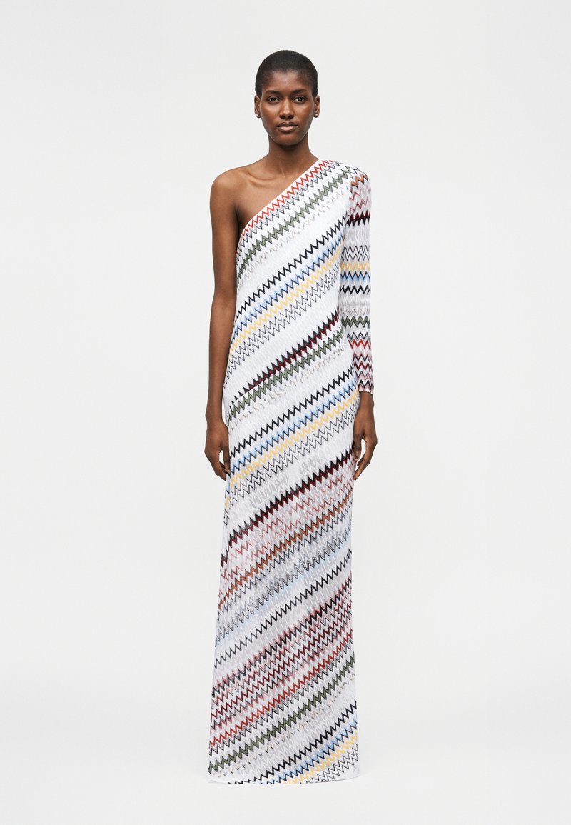 Μοντέλο φορεί μακρύ φόρεμα ενός ώμου με διαγώνια πολύχρωμα ζιγκ ζαγκ σχέδια σε λευκό φόντο.