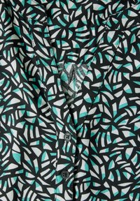 Chemise noire présentant un motif abstrait de formes turquoise et blanches, avec une patte de boutonnage et une texture de tissu douce.