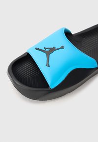 Sort slidesandal med en blå syntetisk rem, der har et sort Jordan-logo. Struktureret sort fodseng for godt greb. Letvægtsdesign.
