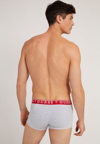 Graue Baumwoll-Boxershorts mit einem roten, markierten Bund. Das Design bietet einen engen Sitz, eine glatte Textur und einen minimalistischen Stil.