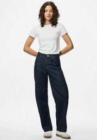 Tumši zils džinsu audums ar platu kāju un augstu jostasvietu, apvienots ar pieguļošu baltu t-kreklu un baltām sporta apaviem. Vienkāršs dizains, bez rakstiem.