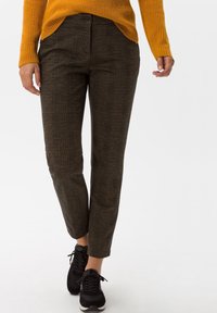 Pantalon à carreaux marron en tissu texturé, avec une coupe droite et une fermeture à bouton à la taille. Associé à des baskets noires.