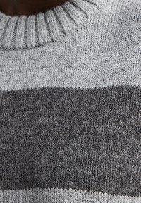 Harmaa neulepusero, jossa on ribbitekniikan kaulus ja vaaleanharmaita ja tummanharmaita vaakasuoria raitoja, valmistettu pehmeästä, teksturoidusta kankaasta.