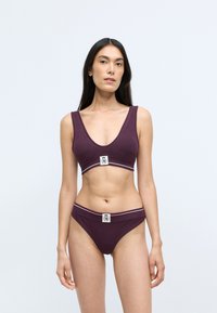 Burgundin bikinisetti, joka sisältää V-mallisen bralette-topin, jossa on logopatch ja yhteensopivat alushousut, joissa on erottuva vyötäröraidan. Sujuva pinta.